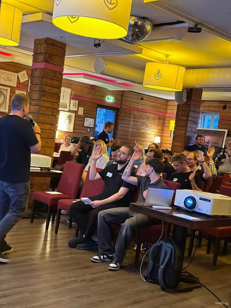 Publikum beim JTL-Stammtisch Berlin 2025 hebt die Hand während des Vortrags